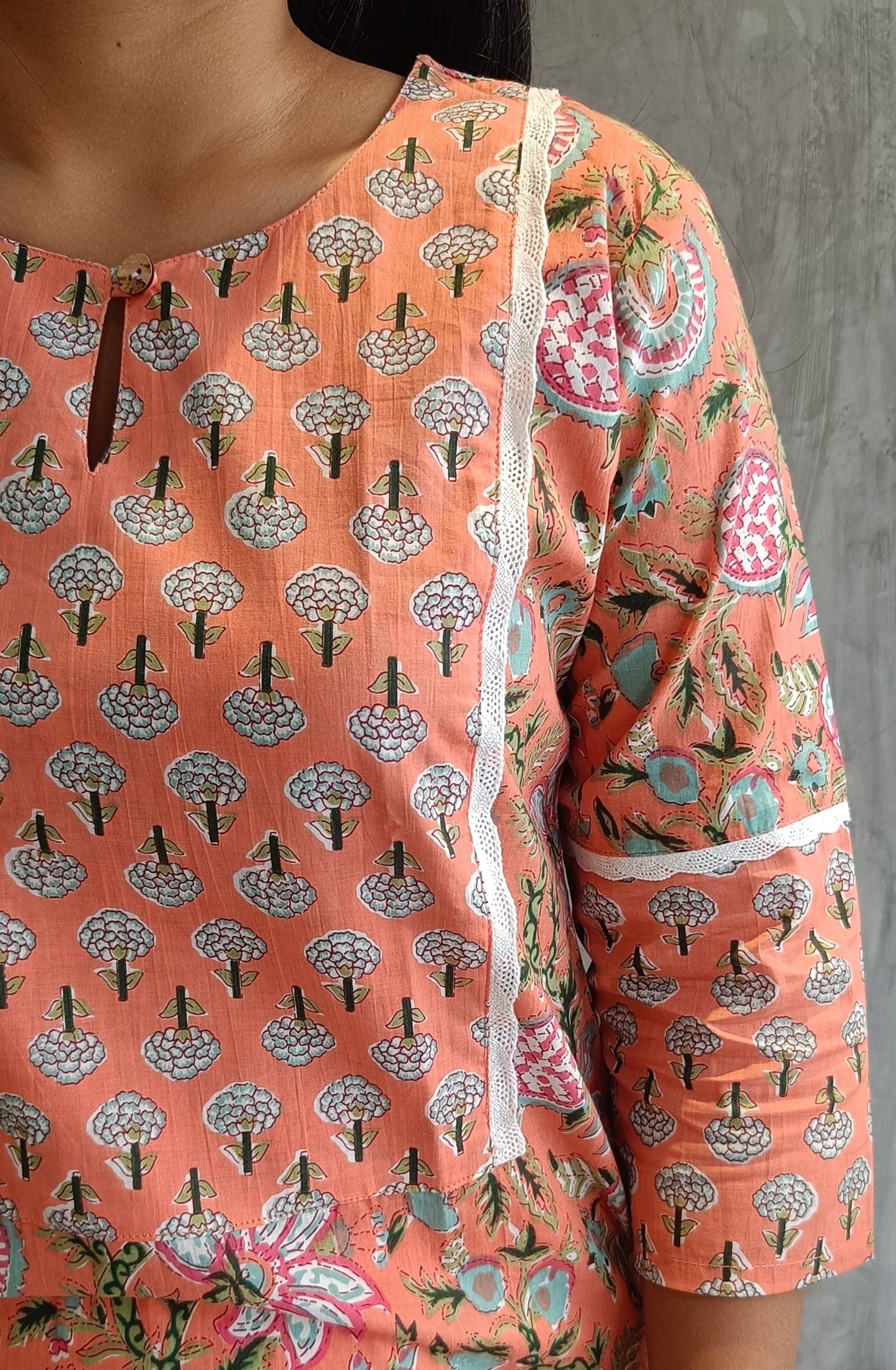 "Side view of a female model in an orange floral handloom cotton kurti by Loomkar, highlighting the kurti's screen-printed ethnic pattern."