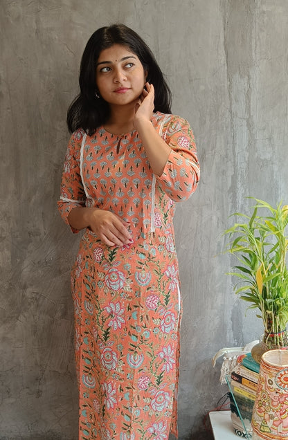 "Front view of a woman wearing a bright orange floral handloom cotton kurti (Loomkar, Raipur) showcasing the kurti's design and fit."