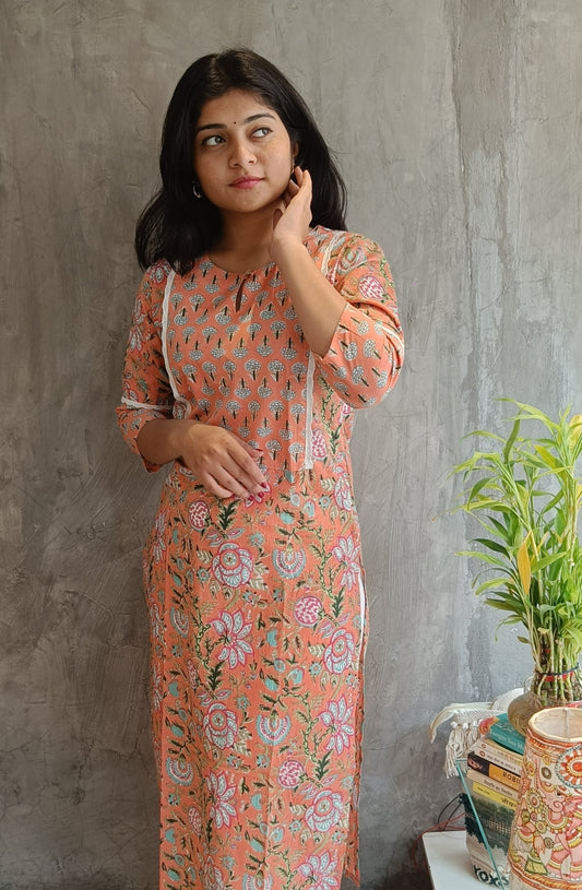 "Front view of a woman wearing a bright orange floral handloom cotton kurti (Loomkar, Raipur) showcasing the kurti's design and fit."